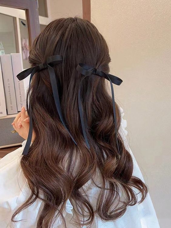 a half updo with little ponytails and waves and black black bows that add a girlish and cute accent