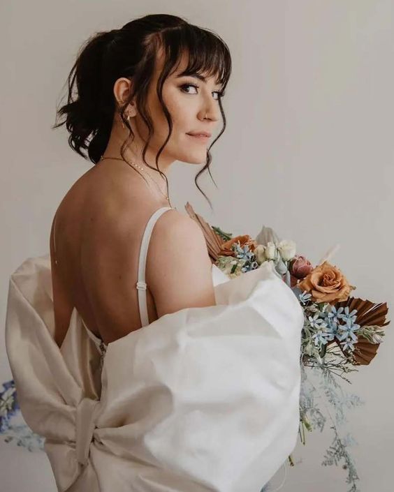a high ponytail on medium hair, with layered bangs and waves down is a cool idea for a wedding