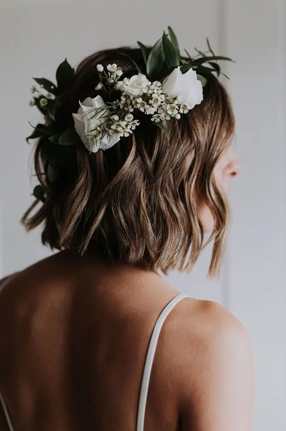 a light brunette wavy long bob accented with white blooms and greenery is a very relaxed wedding hairstyle to try