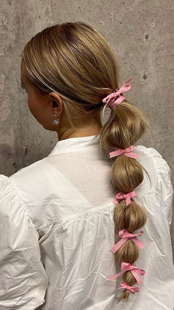 a long bubble braid with a sleek top and pink bows is a cool and super cute hairstyle you can rock every day