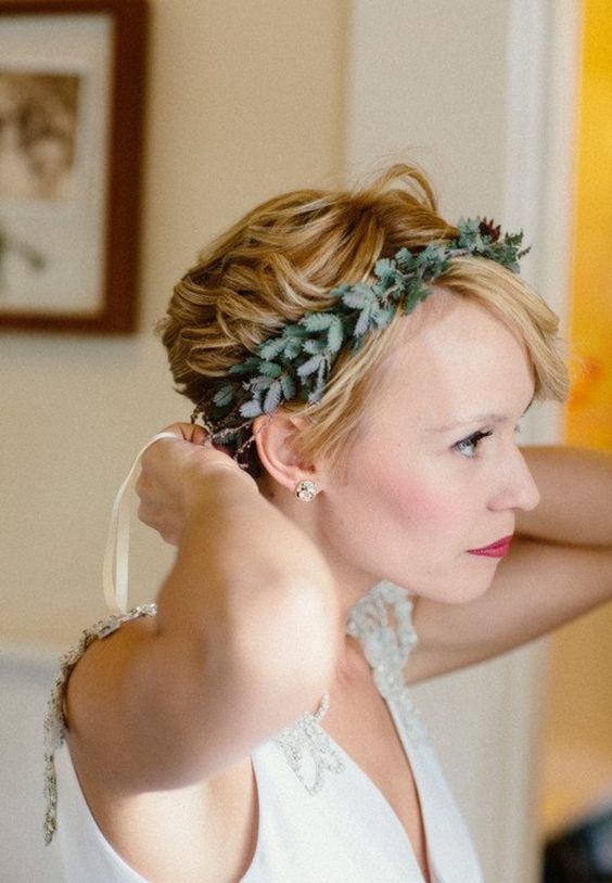 a long honey blonde pixie cut with waves and a greenery crown is a chic and catchy idea for a modern bridal look
