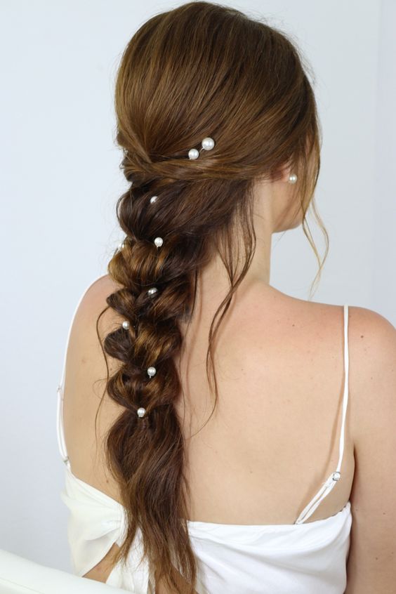 a loose braid with a sleeker top and some pearl hair pins is a cool hairstyle for a more relaxed bride