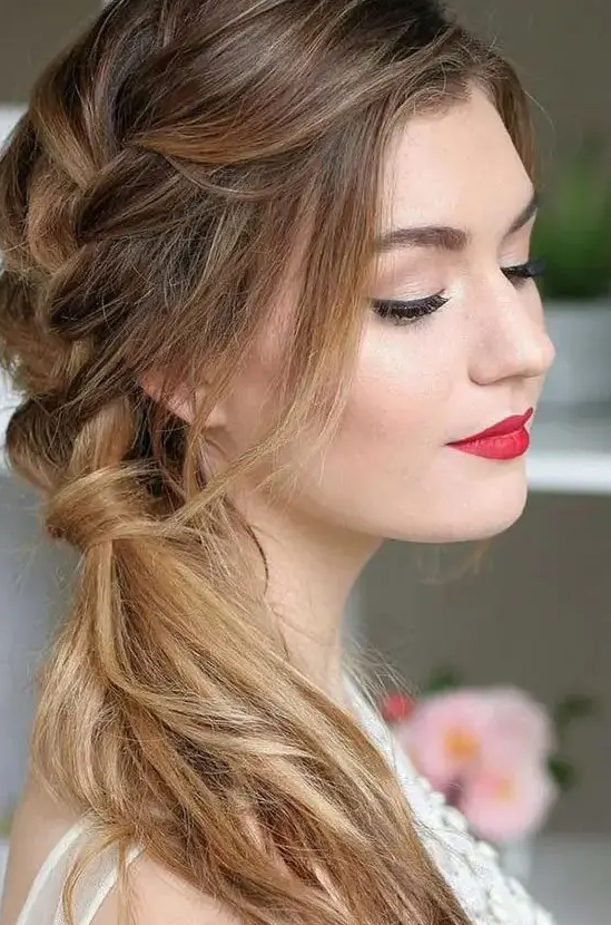 a lovely side swept hairstyle with a side braid coming into a ponytail, with face-framing locks and a slight ombre touch