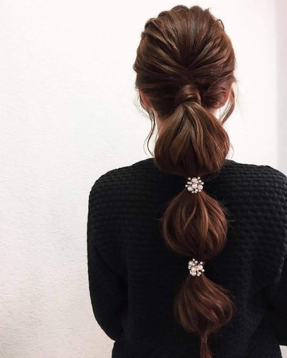a low bubble ponytail with a volume on top and some embellished pieces is a cool idea for a modern wedding