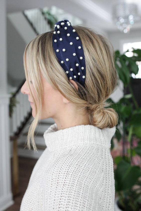 A low bun with a volume on top, face framing bangs and a navy pearl headband are a chic and feminine combo to try