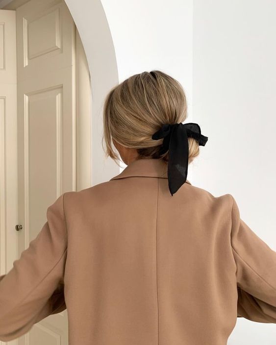 a low bun with a volumetric top and a black bow for an accent are a cool and pretty look for every day