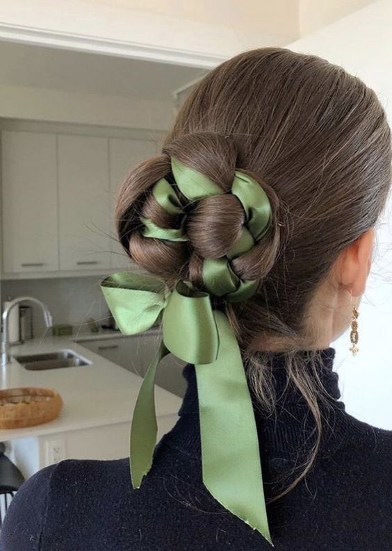 a low bun with a volumetric top and a green ribbon interwoven into the bun plus a ribbon bow for an accent