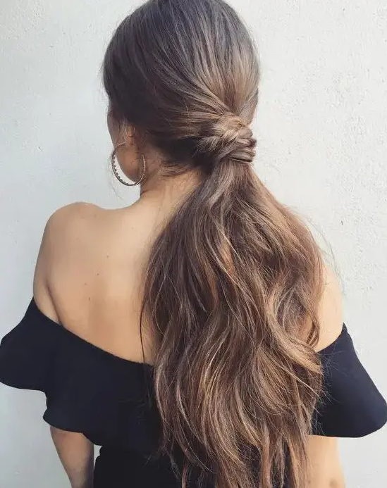 a low ponytail with a sleek top, a twisted and braided part and much dimension on the ends