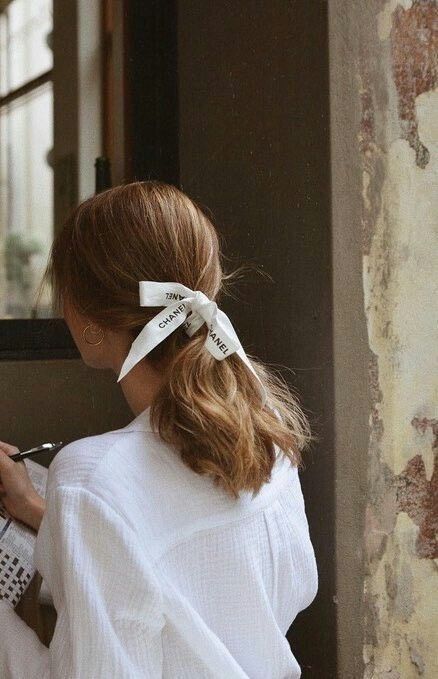 a low ponytail with much volume and a delicate white Chanel ribbon styled as a bow is lovely