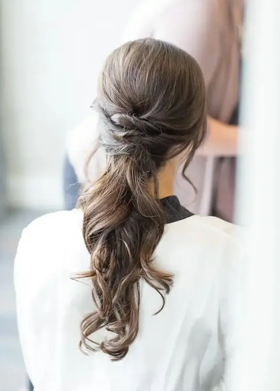 a low ponytail with twists and waves and no detailing and accessories for a modern bride