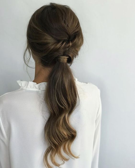a low ponytail with twists and waves is a cool idea for a more casual bridal look