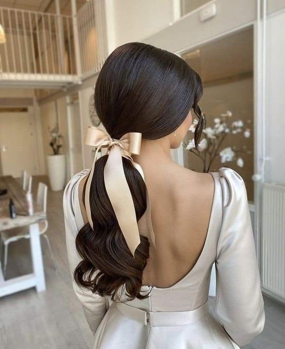a low ponytail with waves and a sleek top plus a tan silk bow to add a more refined feel to the outfit