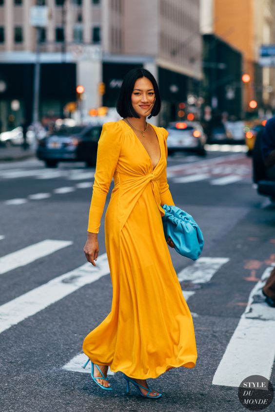 a mellow yellow maxi dress with a plunging neckline, a draped bodice, bold blue strappy shoes and a bag for a spring wedding