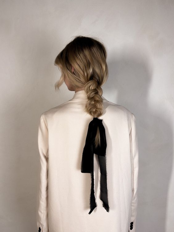 a messy and loose low braid with a messy top and face-framing hair, a black ribbon bow are a lovely combo for every day, it looks chic