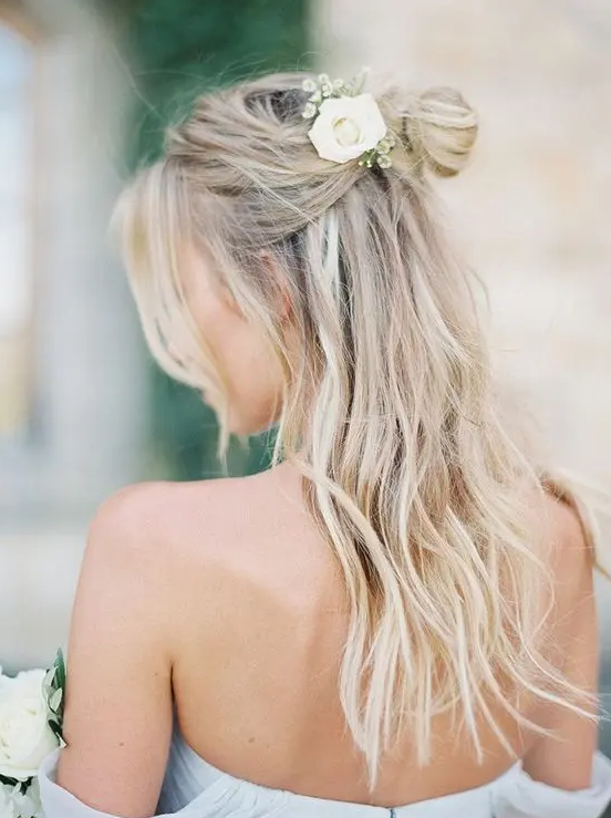A messy half down hairstyle with fresh flowers is a cool idea for a hot day wedding or a destination one