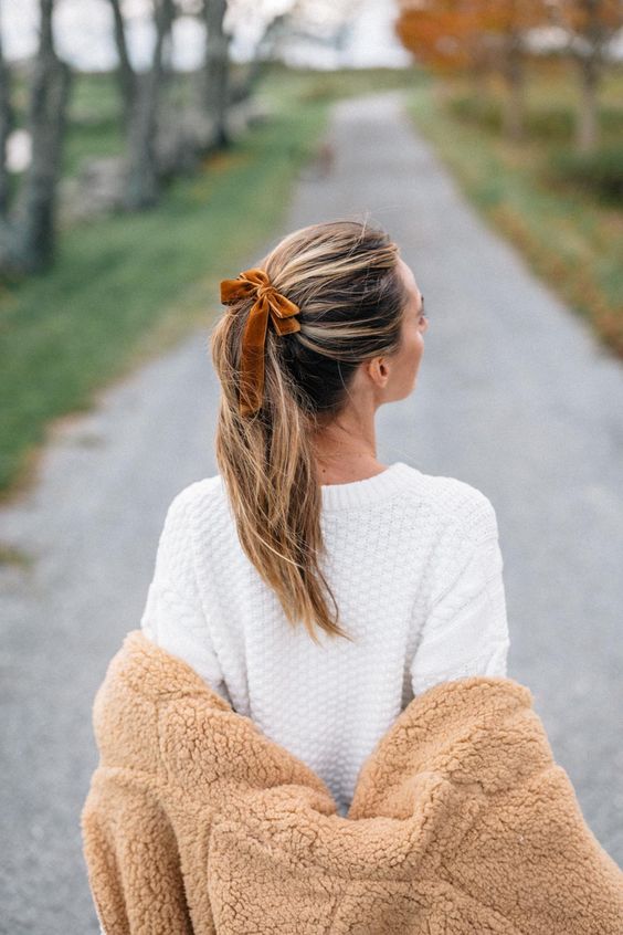 a messy high ponytail with a messy top and a rust velvet bow are a lovely and cute combo for any outfit