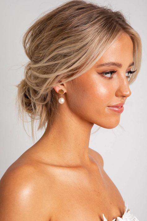 a messy low bun with some volume and texture is a cool hairstyle that is easy to realize for a wedding