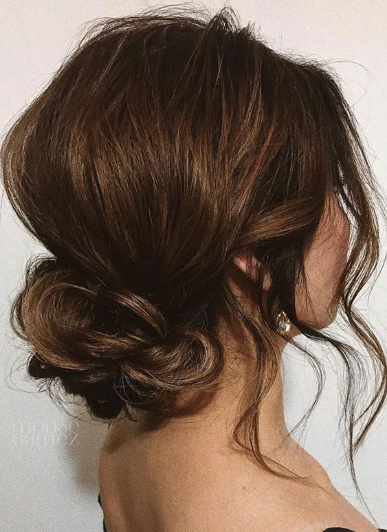 a messy low twisted bun with a bump and some waves framing the face is a cool casual hairstyle to rock