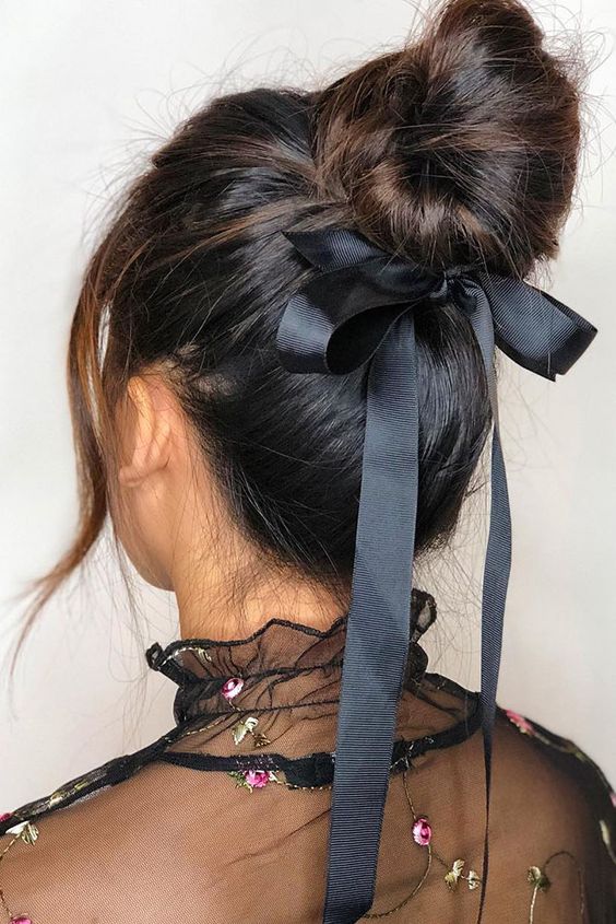 a messy top knot, a volume on top and face-framing hair plus a black bow are a lovely combo for a party