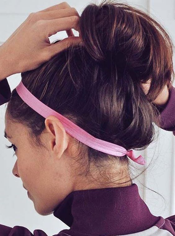 a messy top knot with a messy top and a pink headband to keep the hair off the face are a lovely idea