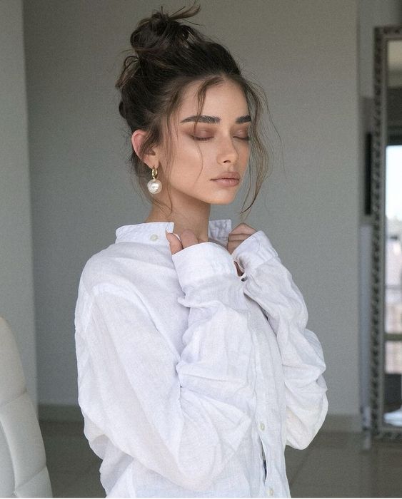a messy top knot with a messy volume on top and some hair down is a cool idea for a casual and relaxed bridal look