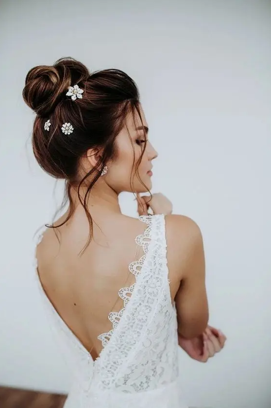 a messy top knot with a volume on top and some face-framing locks down plus some embellished hair pins