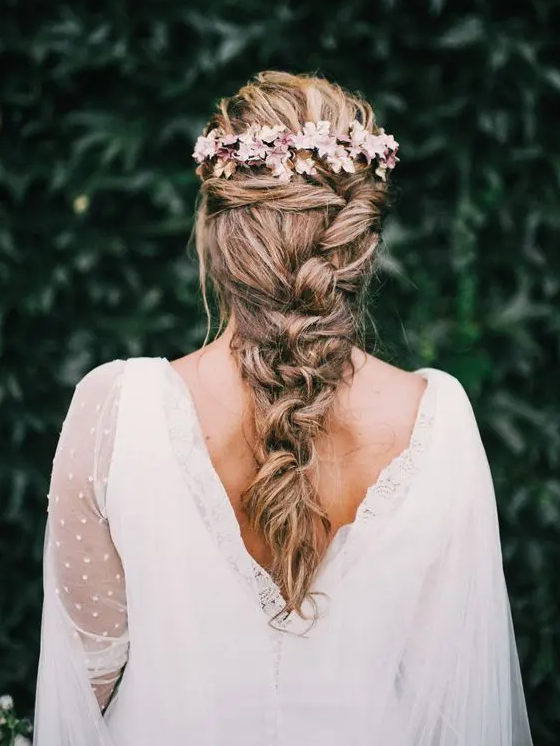 a messy twisted braid with more twists on top and some fresh blooms is a cool idea for a refined spring or summer wedding