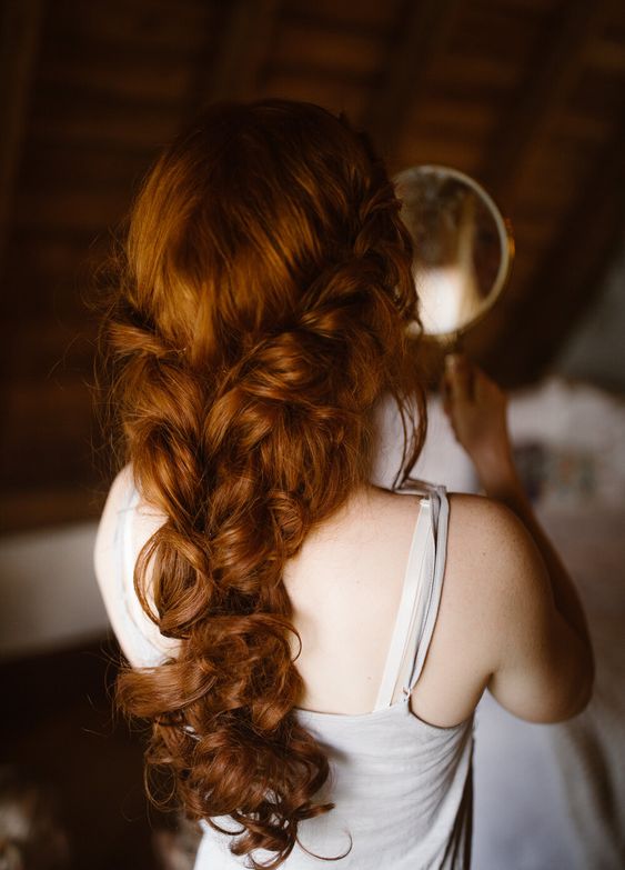 a messy wavy braid with a braided halo is a cool and chic solution for a more relaxed bridal look