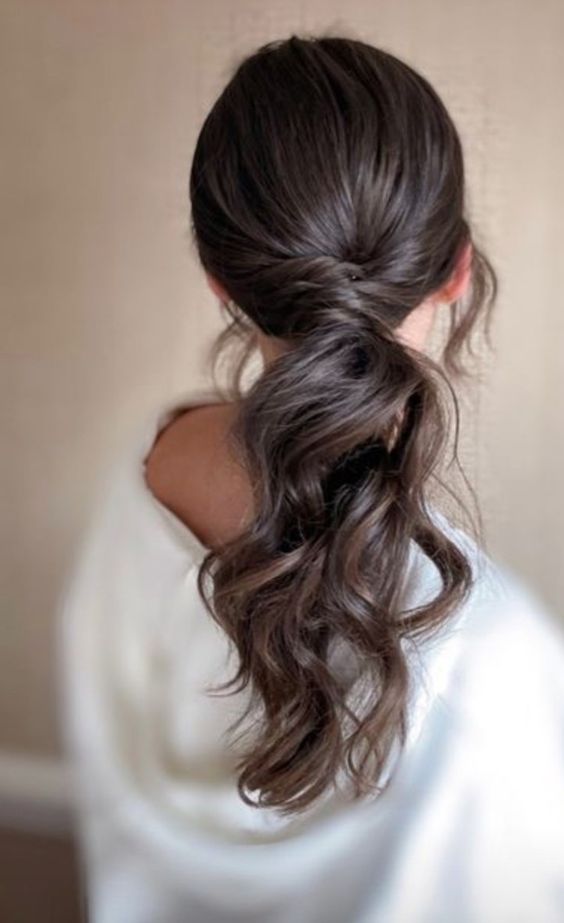 A messy wavy ponytail with a volumetric top and some face framing hair is a gorgeous idea for a wedding