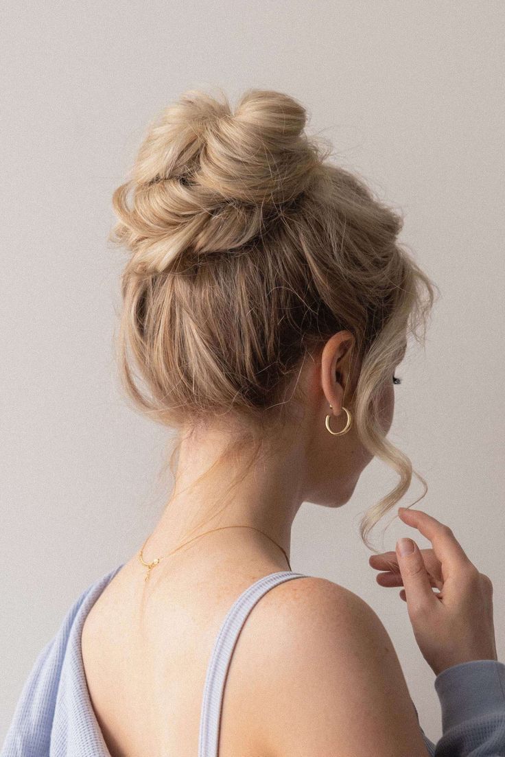 a messy wrapped high bun with messy top and waves framing the face is a very cool and catchy idea for a wedding