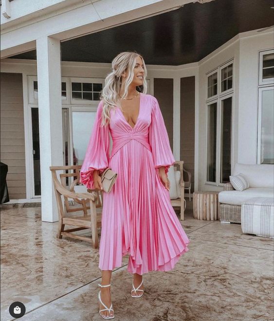 a metallic pink midi dress with a plunging neckline, pleated bell sleeves and a skirt, white strappy shoes and a neutral clutch