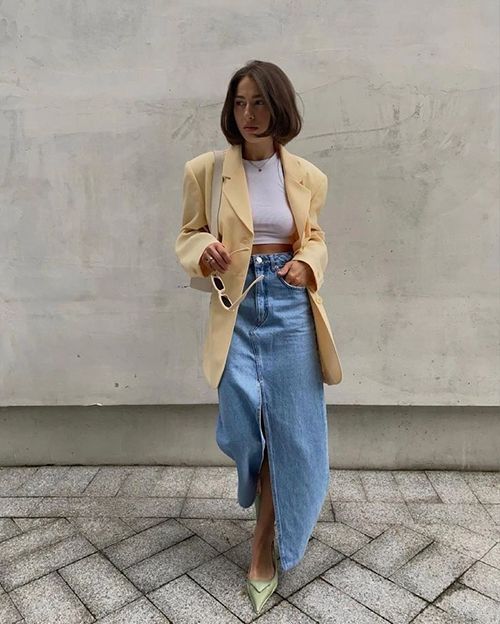 a modern spring look with a white crop top, a blue denim maxi skirt, an oversized yellow blazer, green shoes and a neutral bag