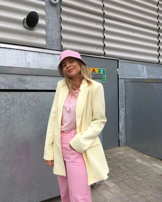 A pastel spring outfit with a pink t shirt and jeans, a pink bucket hat, a yellow blazer is comfy