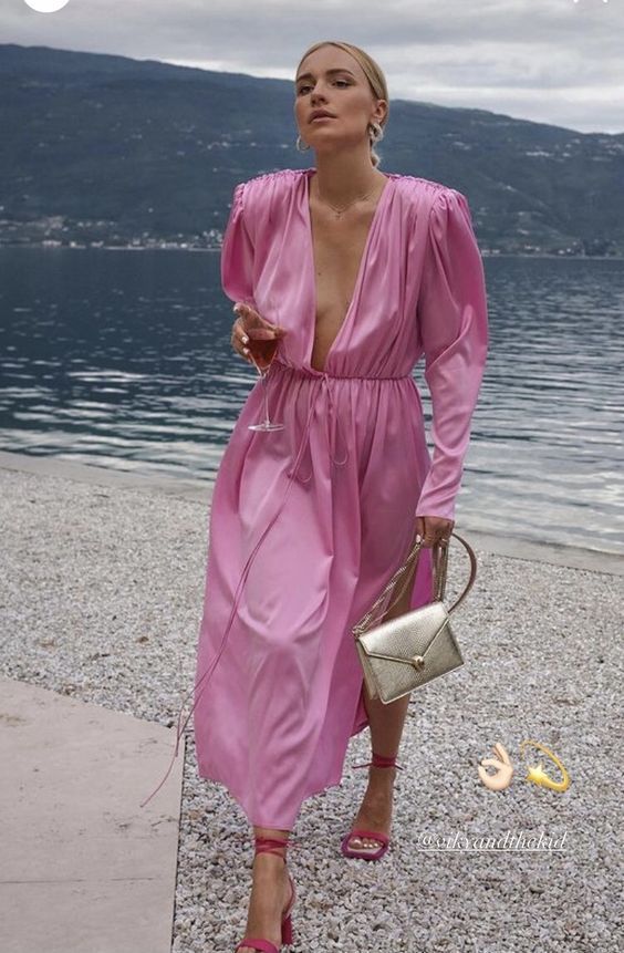 a pink midi dress with a plunging neckline and long sleeves, a silver bag and pink lace up shoes
