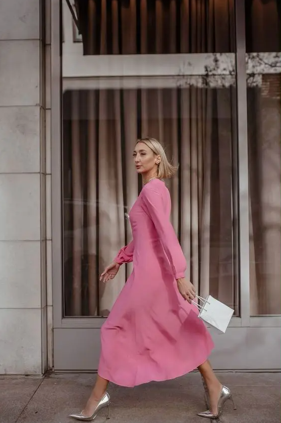a plain pink midi dress with long sleeves, silver heels and a small white bag for a chic spring wedding guest look
