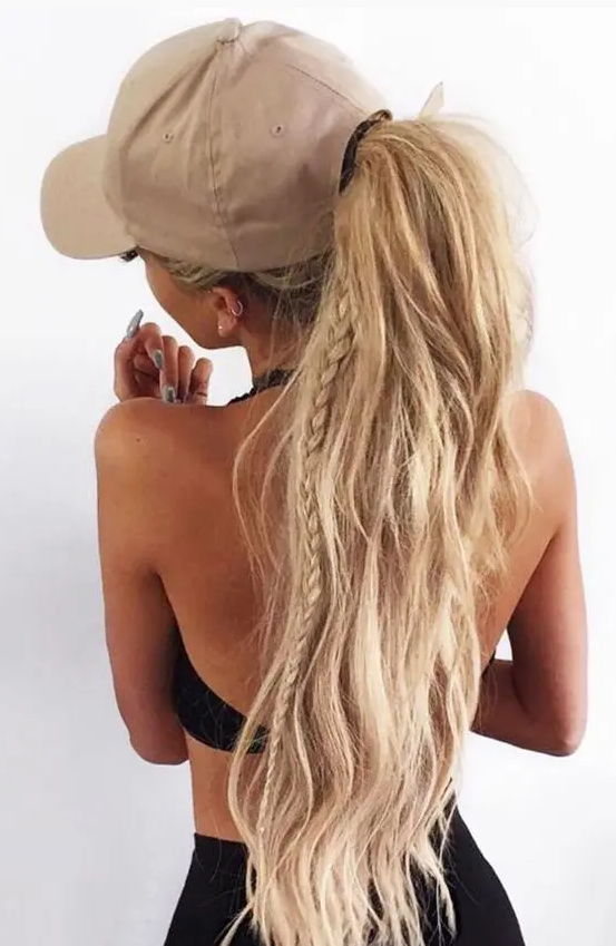 a ponytail with a little braid and textural hair plus a baseball cap for a chic and comfy look