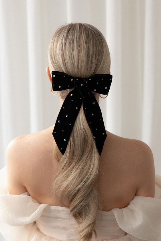 a refined low ponytail with a sleek top and a embellished black velvet bow is an amazing idea for any formal look and party