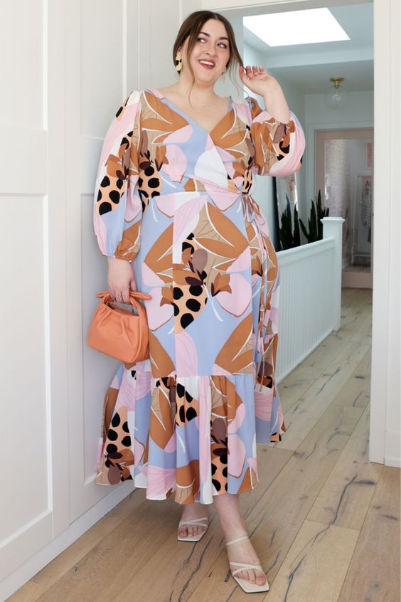 a romantic pastel abstract print maxi dress with a V neckline and long sleeves, white strappy shoes and an orange mini bag