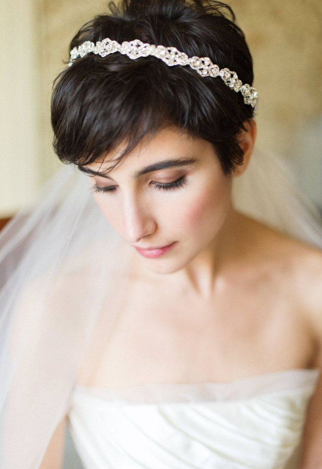 a short pixie haircut with bangs and a rhinestone hairpiece plus a veil is a lovely hairstyle that looks chic and elegant