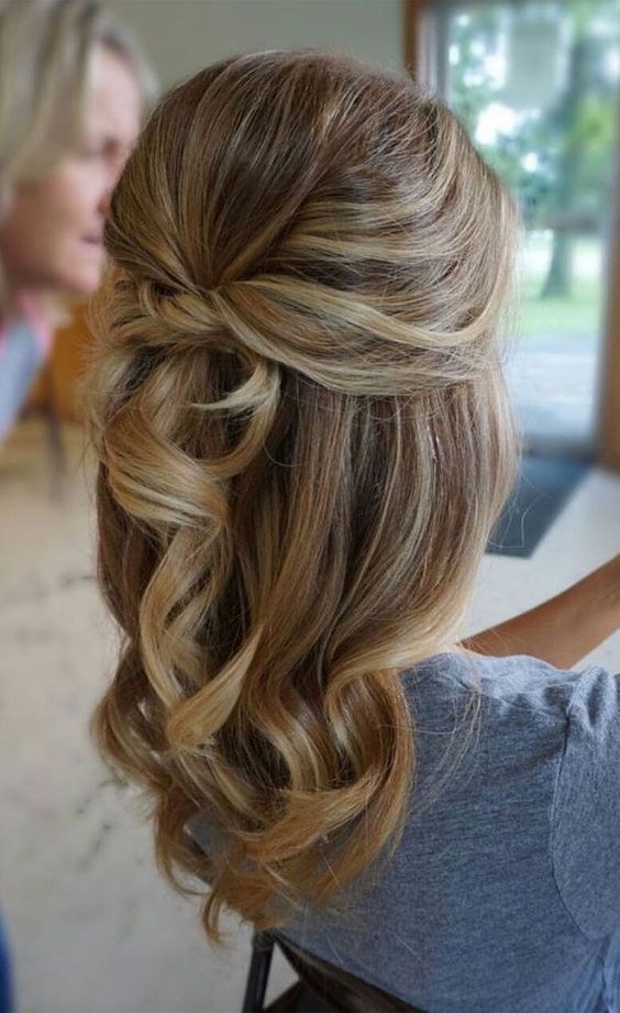 a simple and cool half updo with a bump on top, a knot and waves down looks elegant and stylish
