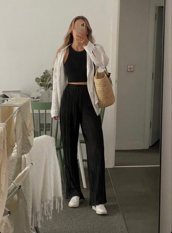 a spring look with a black top and trosuers, a white button down, white sneakers, a woven tote