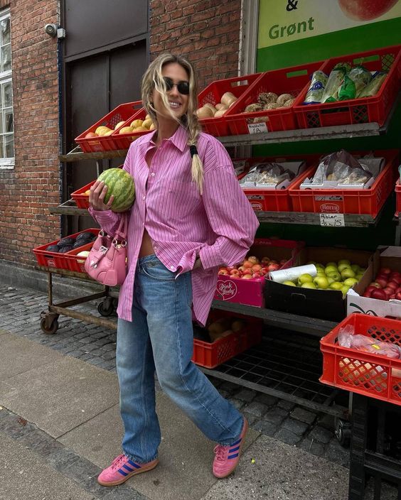 a spring look with an oversized pink button down, blue jeans, pink Samba sneakers and a pink bag