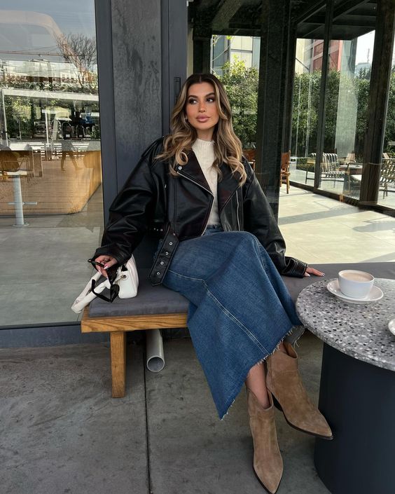 a spring outfit with a white top, a  navy denim maxi, brown suede boots, an oversized black leather jacket and a small white bag