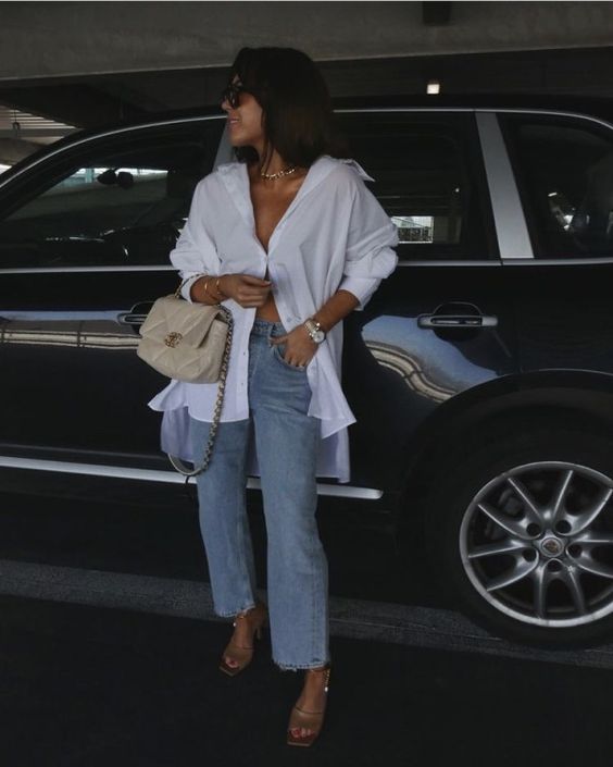 a spring to summer look with an oversized button down, blue jeans, nude mules and a creamy bag with chain