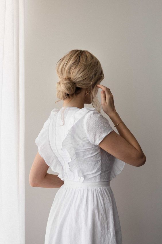 a tight yet messy low bun with a messy volume on top and some hair down is a cool hairstyle for a casual bridal look