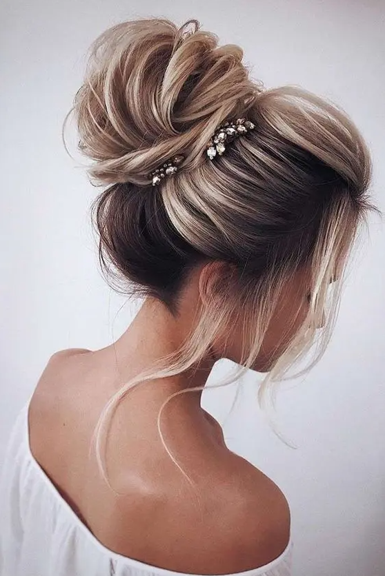 a voluminous and textural top knot with a bump, some locks down and a couple of thinestone hairpieces