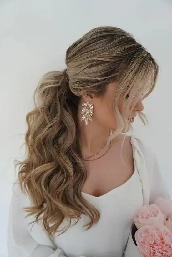 A voluminous wavy ponytail with a bump on top and face framing hair is adorable for most bridal styles