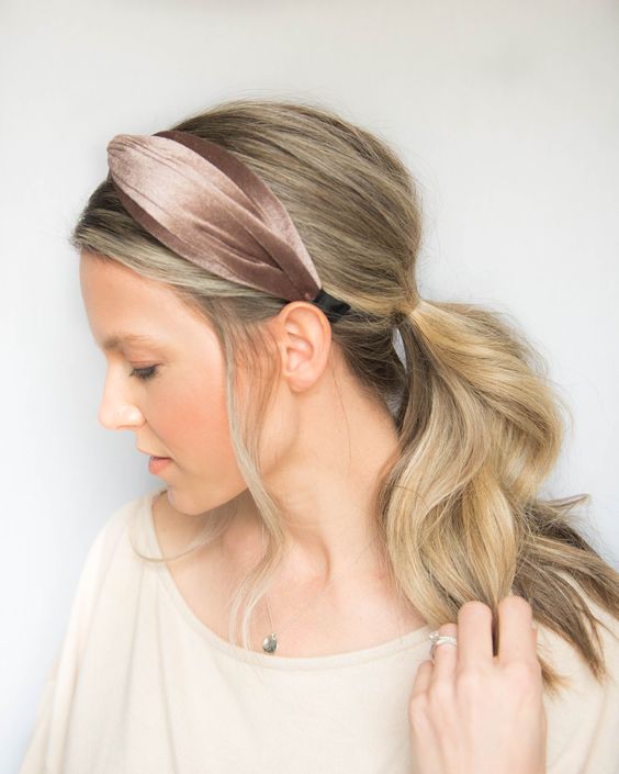 a wavy low ponytail with a volume on top and waves down plus a brown velvet headband for a chic look