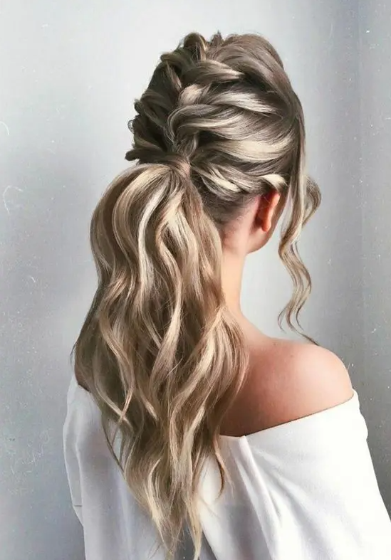 a wavy twisted braid coming into a low wavy ponytail, with locks framing the face is a lovely idea for a wedding