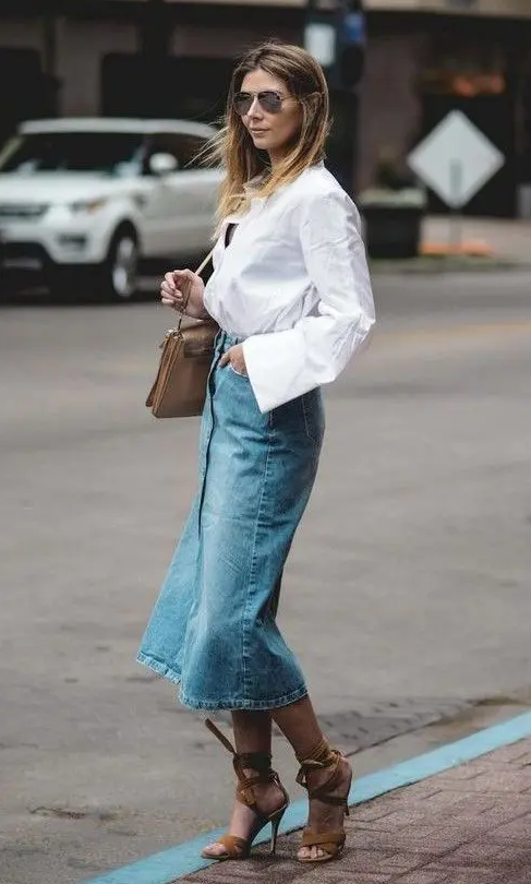 a white linen shirt, a blue denim midi skirt, brown lace up heels, a brown bag and sunglasses for a chic and relaxed look